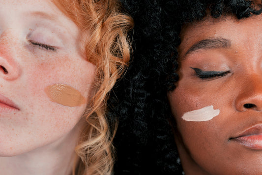 Close-up of an African and Caucasian woman’s face with smooth, radiant skin, showcasing natural beauty with minimal foundation.