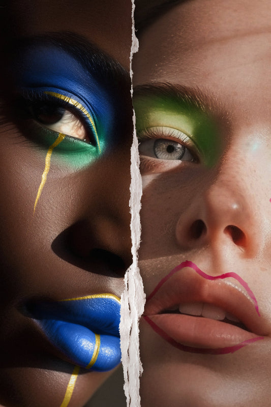 Close-up portrait of a woman with bold, artistic makeup, featuring bright eyeshadow and eyeliner, showcasing a cheerful and confident expression.